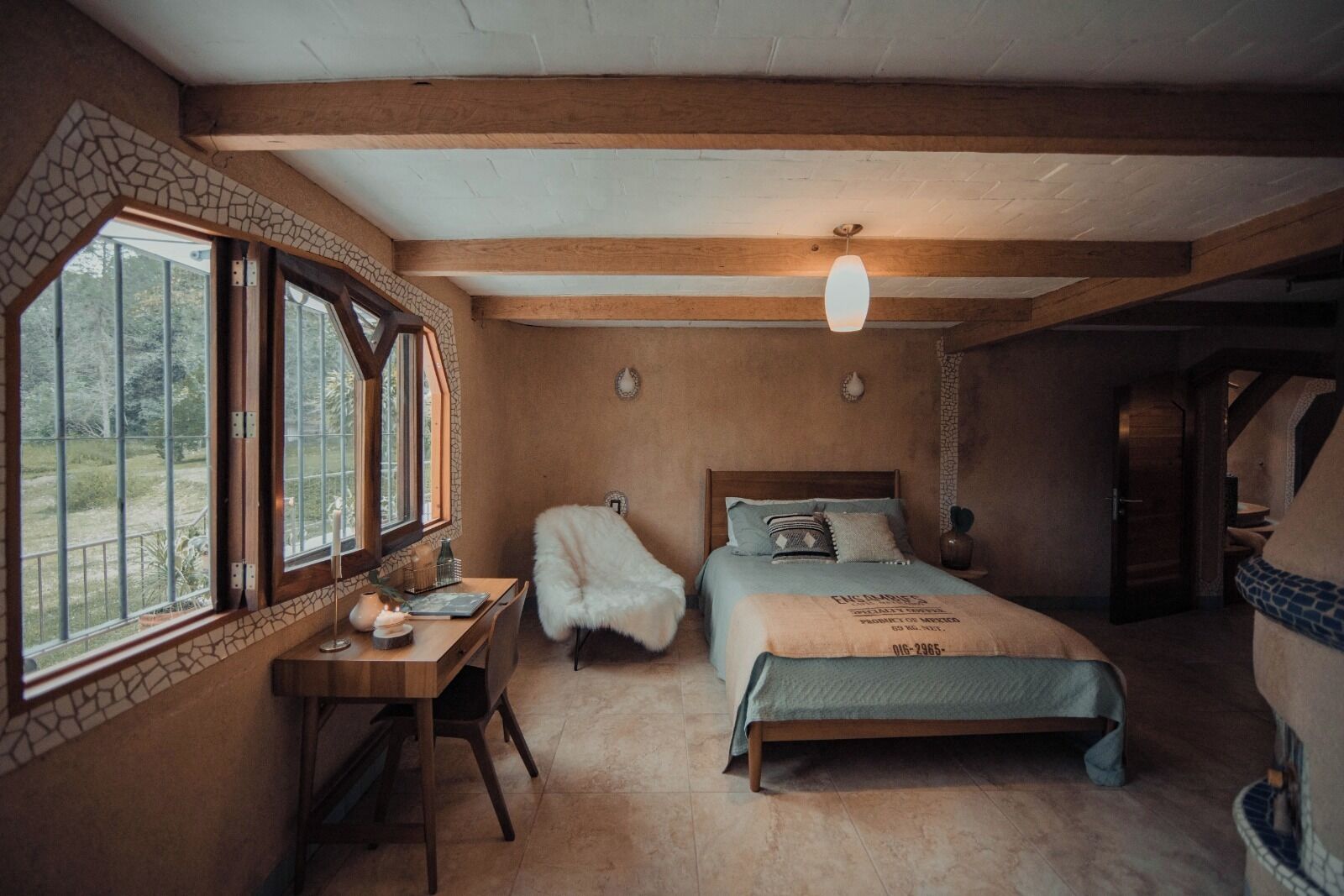 Ein Schlafzimmer mit einem Bett, einem Schreibtisch und einem Stuhl. Ein Fenster bietet Blick auf eine grüne Landschaft.