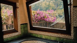 A bathroom with mosaic tile flooring, a bathtub, and two windows with views of pink flowers. - EL EQUIMITE HOTEL BOUTIQUE (Coatepec)