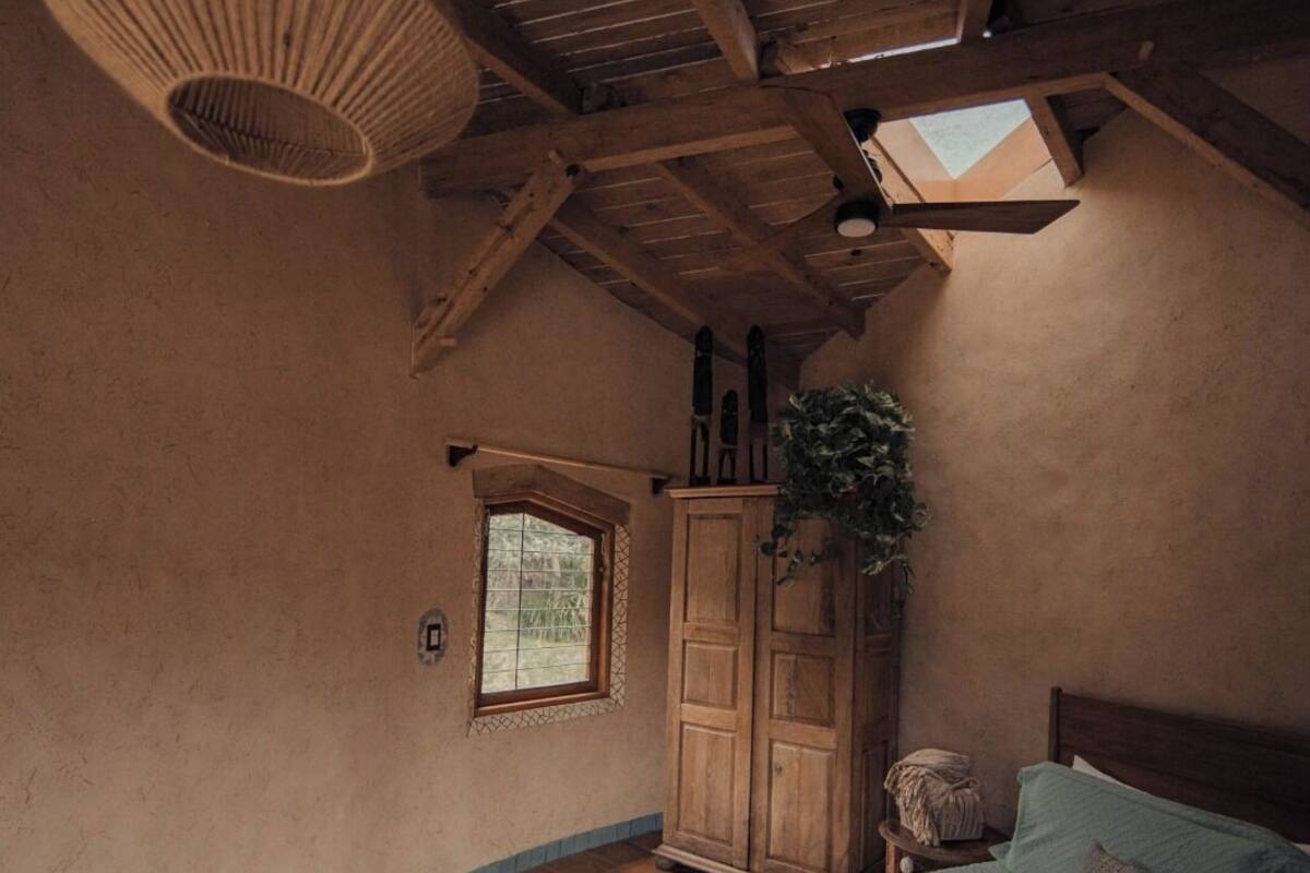 A bedroom with a bed, a wardrobe, a hanging light fixture, a window, and a skylight.