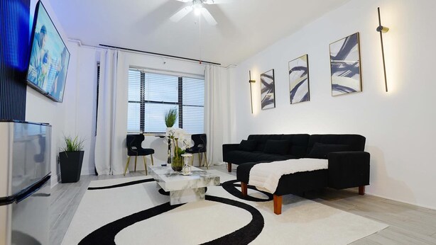 A modern living room with a black sofa, a marble coffee table, and abstract wall art.