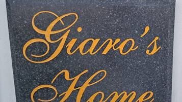 Eine dunkle, strukturierte Wand mit der Aufschrift 'Giaro's Home' in goldener, verspielter Schrift.