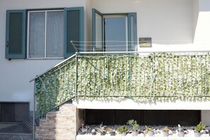 A building with a staircase, a balcony with a climbing plant, and potted plants at the base. - Giaro's Home (Pompei)