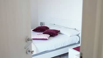 Een slaapkamer met een bed, nachtkastje, lamp en een kunstwerk aan de muur.