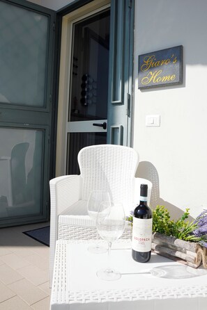 A white wicker chair and table set outside a door with a sign above it. - Giaro's Home (Pompei)