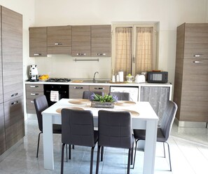 A modern kitchen with a dining table, chairs, and various appliances. - Giaro's Home (Pompei)