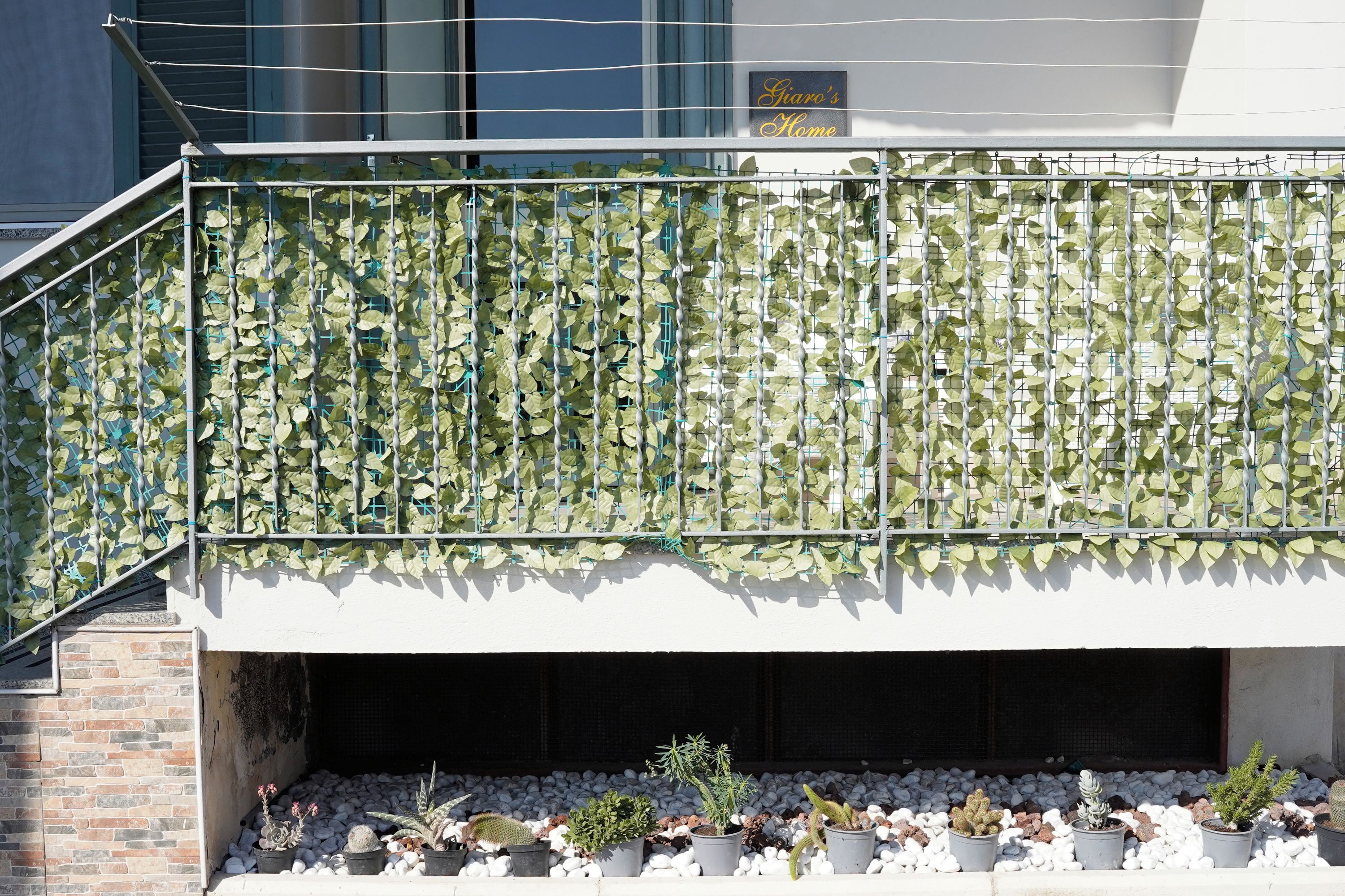 Un balcone con ringhiera in metallo e un muro ricoperto di vegetazione verde.
