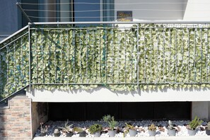 A balcony with a metal railing and a wall covered in green foliage. - Giaro's Home (Pompei)