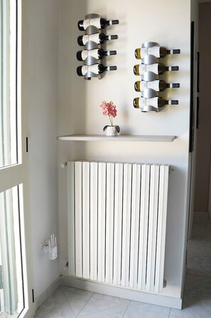 Een kamer met een witte radiator, een plank met flessen en een bloevas.