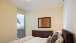 Una camera da letto con un letto, un comodino e un tavolino. Si vede una finestra con vista sull'esterno.