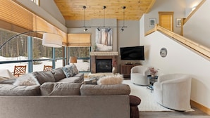 A modern living room with a fireplace, a TV, and a staircase. - St8716-3 (Keystone)