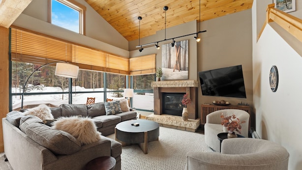 A modern living room with a fireplace, large windows, and a television. - St8716-3 (Keystone)