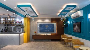 A modern living room with a marble floor, a central TV, a coffee machine, and a bar area with shelves and decorative items. - Diamond Corners Serviced Apartments (Madinah)
