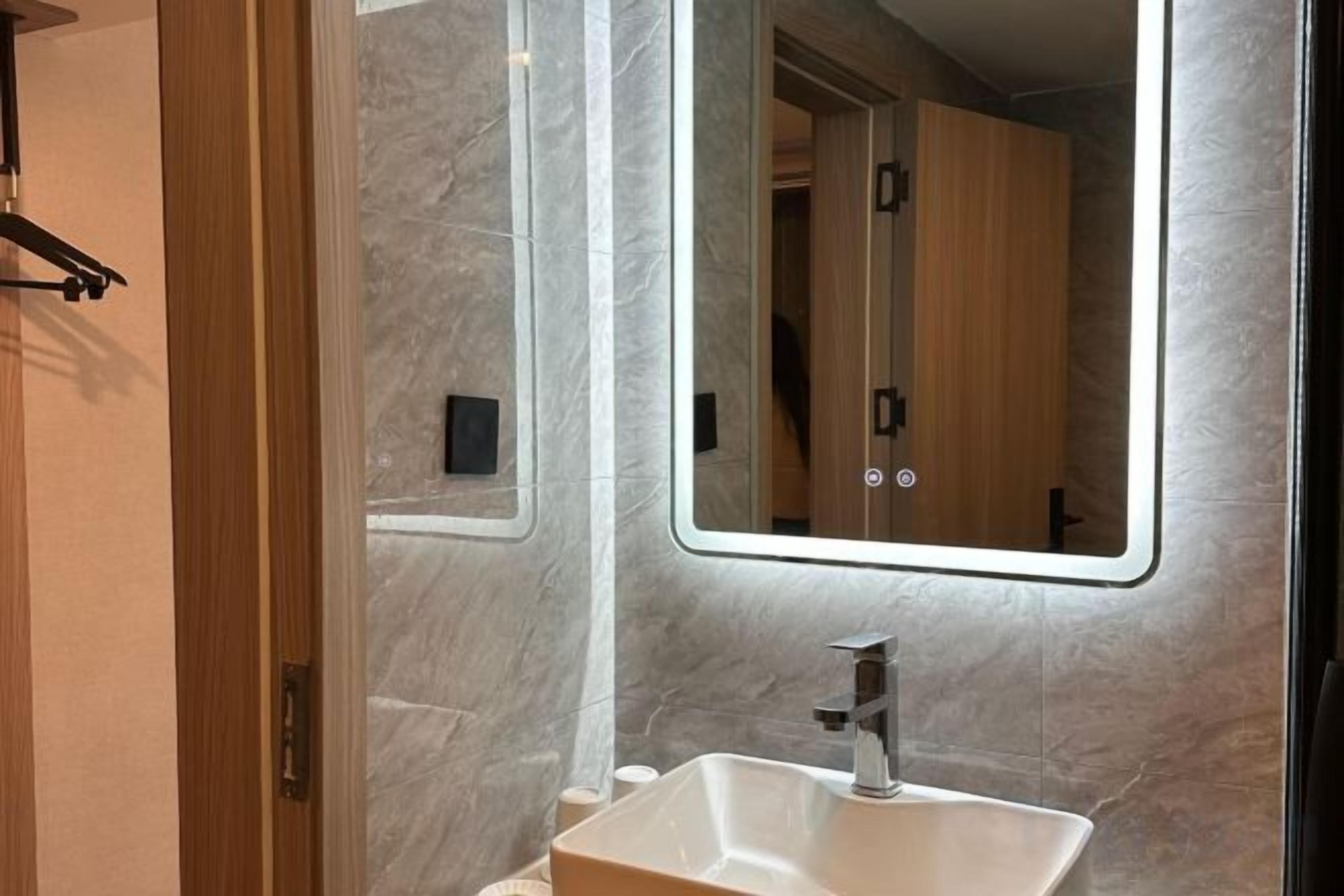 A bathroom with a marble wall, a sink, and a mirror.