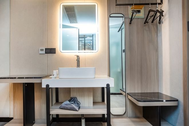 Un baño moderno con un lavabo blanco, un espejo y un perchero para toallas.