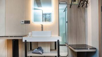 Un baño moderno con un lavabo blanco, un espejo y un perchero para toallas.