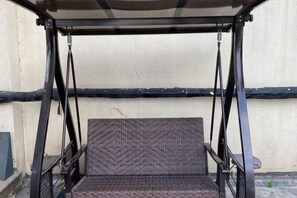 A swing seat with a metal frame and a woven seat cushion, attached to a metal canopy. - GreenTree Inn (Shanghai Gongfu Xincun Metro Station) (Shanghai)