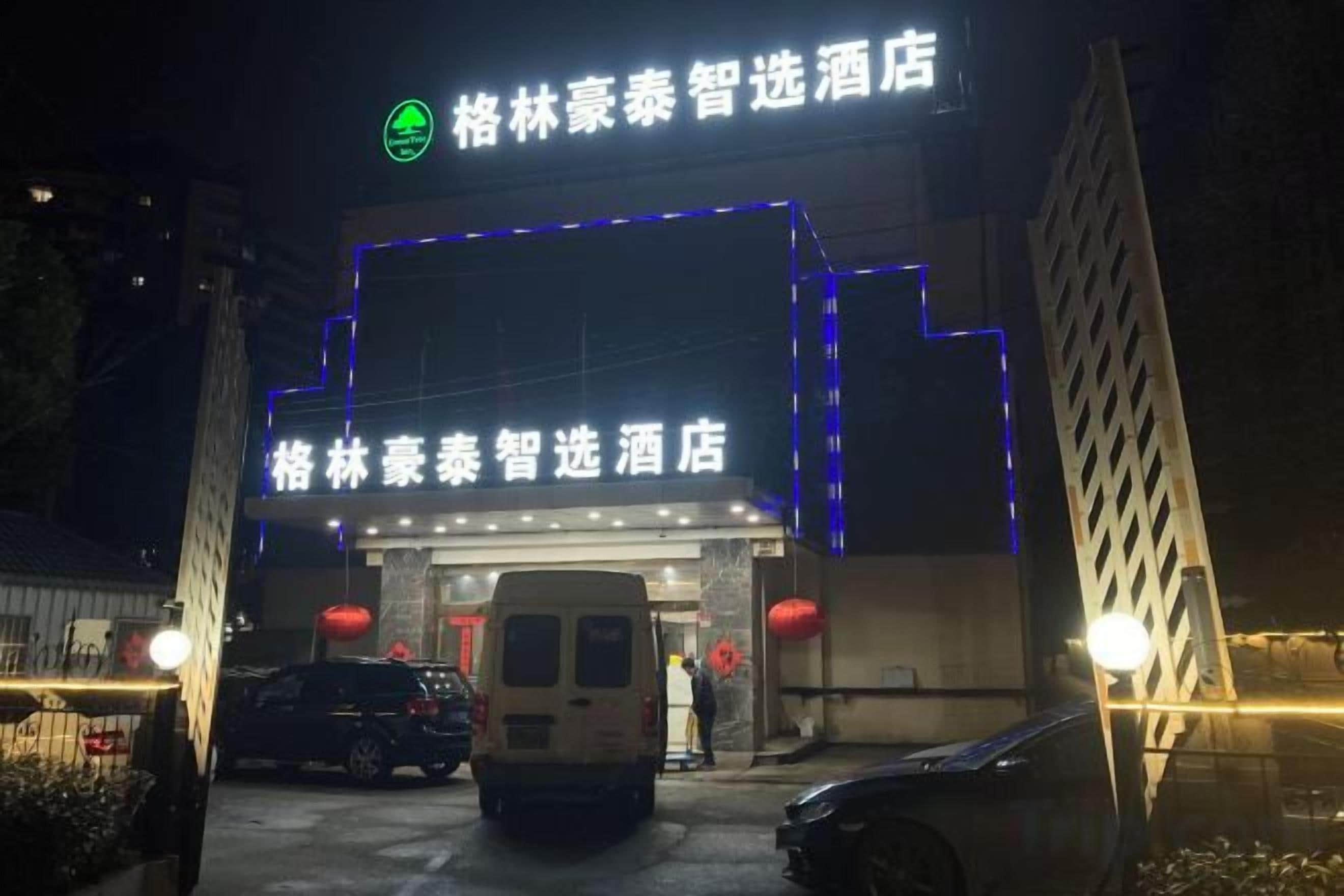 A hotel entrance with illuminated signage and a van parked in front.