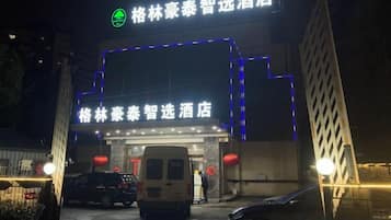 A hotel entrance with illuminated signage and a van parked in front.