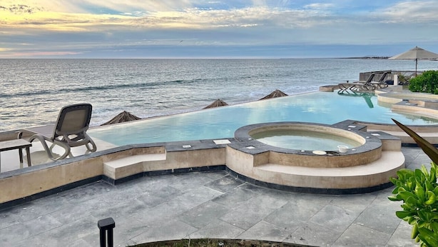Un área de piscina con jacuzzi, sillas de descanso y vistas al mar.