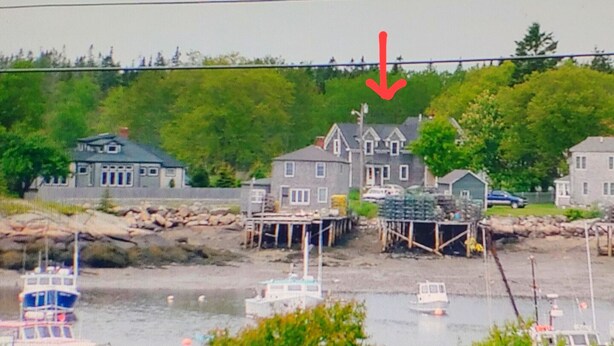 Une propriété située au bord de l’eau, avec plusieurs bateaux amarrés, une zone de quai et des immeubles résidentiels en arrière-plan.
