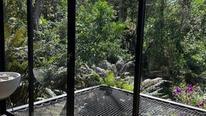 Quarto com vista para um jardim exuberante através de uma janela de tela.