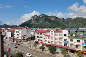 A town with buildings, a road, and mountains in the background. - Wuyishan Mushi Time Hotel (Impression Dahongpao Store) (Wuyishan)
