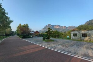 A paved pathway leading to a building with a mountain backdrop. - Wuyishan Mushi Time Hotel (Impression Dahongpao Store) (Wuyishan)