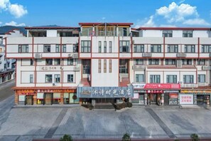 A multi-story building with a central entrance, multiple windows, and signage indicating a hotel. - Wuyishan Mushi Time Hotel (Impression Dahongpao Store) (Wuyishan)