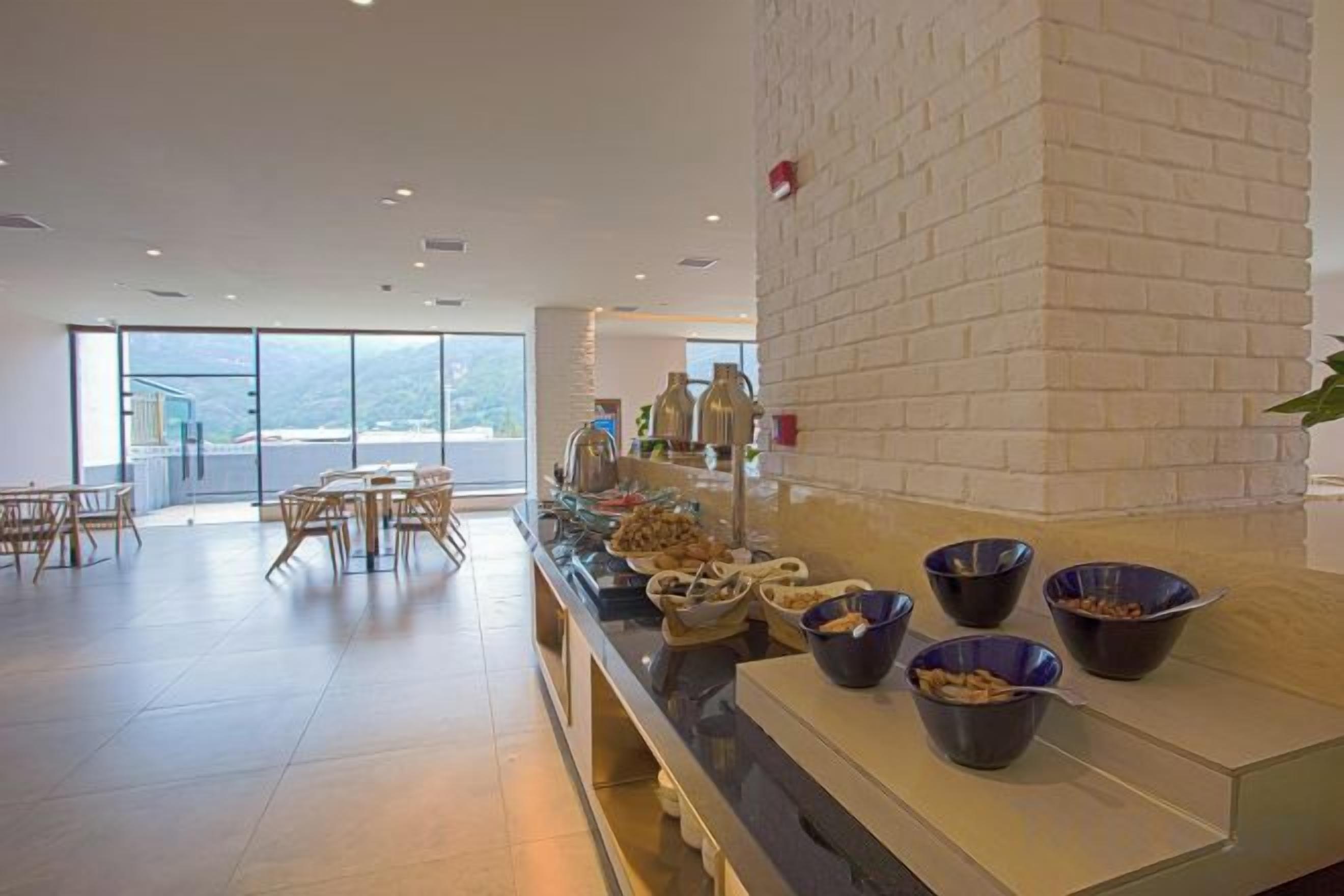 A buffet area with a long counter, bowls of food, and a seating area with tables and chairs.