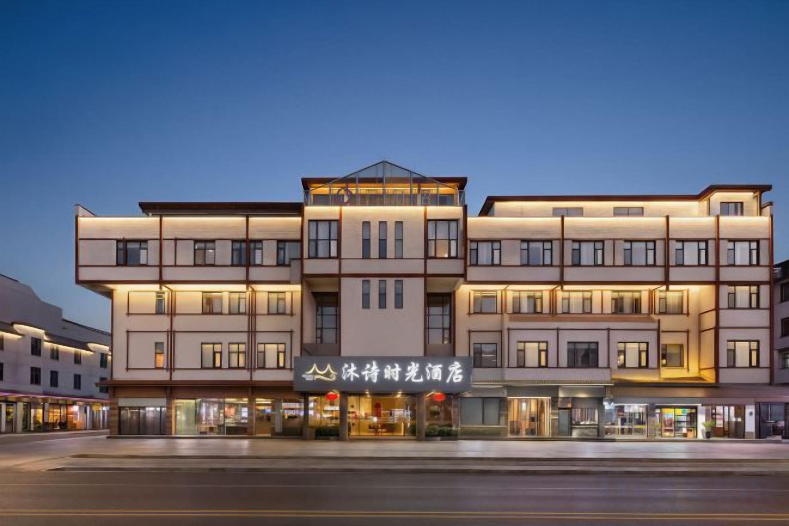 Un hotel de varios pisos con fachada moderna, múltiples balcones y una entrada destacada con señalización.