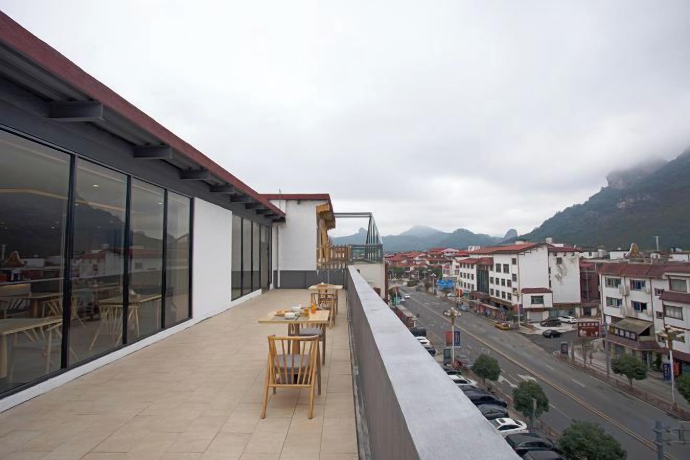 A balcony with outdoor seating and a view of a street and buildings.