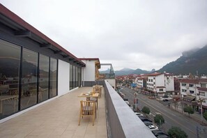A balcony with outdoor seating and a view of a street and buildings. - Wuyishan Mushi Time Hotel (Impression Dahongpao Store) (Wuyishan)