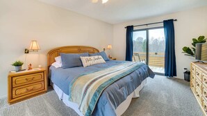 Une chambre à coucher comprenant un lit, des tables de chevet, une commode, un ventilateur de plafond et une vue sur l’extérieur.