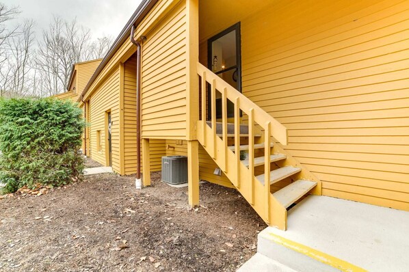 A yellow house with a wooden staircase leading to a porch.