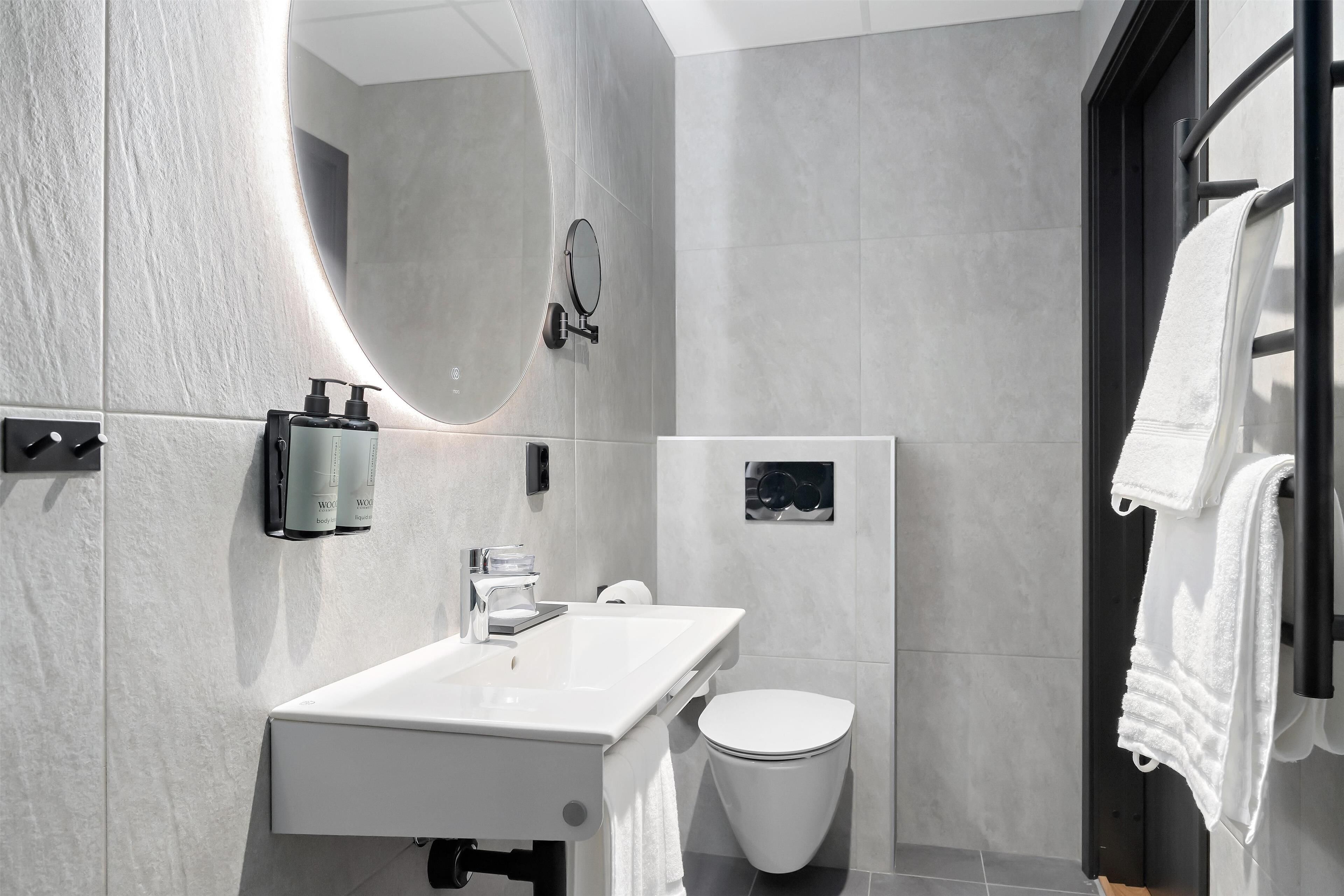 Une salle de bain moderne avec un lavabo blanc, des toilettes et un porte-serviettes.