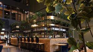 A modern bar area with a curved counter, multiple seating options, and indoor plants. - Hotel Riverside Avesta, BW Signature Collection (Avesta)