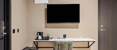 Un espacio de oficina pequeño y moderno con un escritorio, una silla y un televisor de pantalla plana montado.