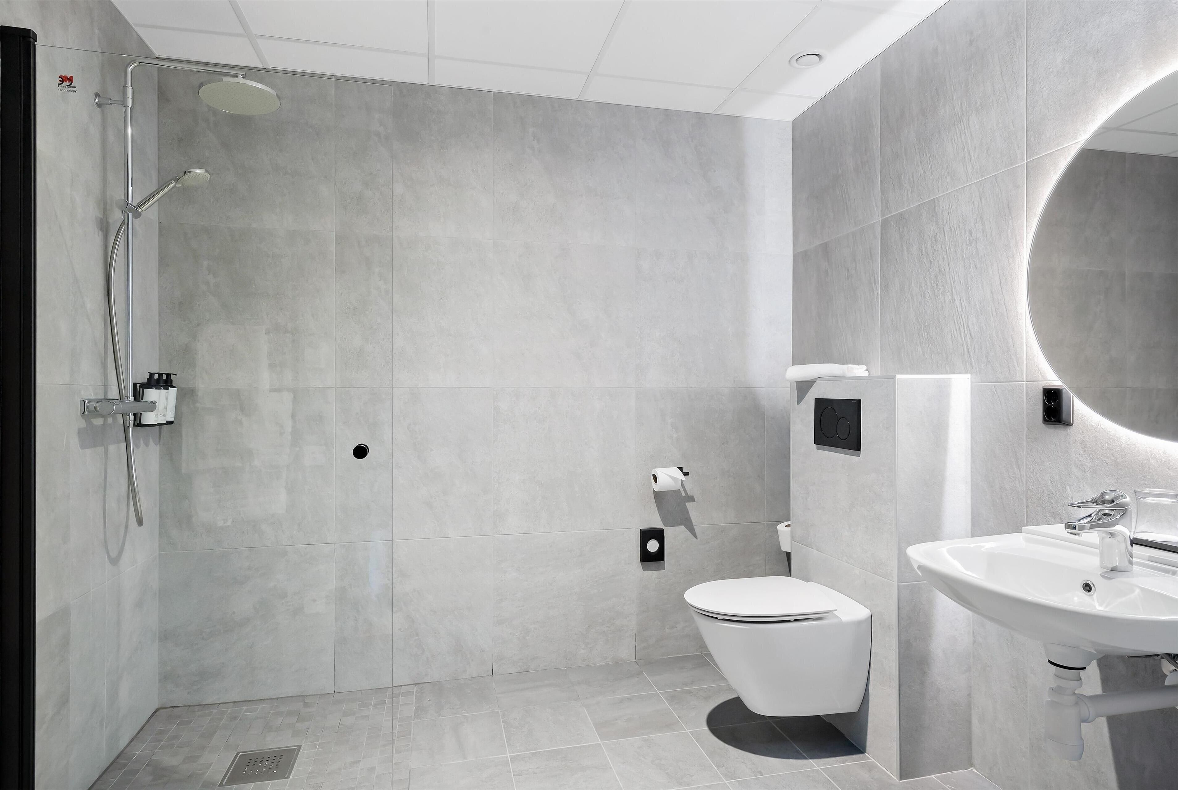 Un bagno moderno dotato di doccia, WC e lavandino.