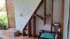 Eine Holzterrasse mit integriertem Sitzbereich, einer Treppe und einem an der Wand befestigten Regal mit Dekoration.