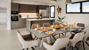 A modern dining area with a large table set for breakfast, surrounded by comfortable chairs.