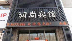 Une enseigne d’hôtel portant le nom « Shouxiang Hotel » et un numéro de téléphone.