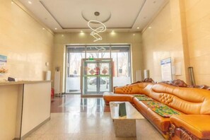 A reception area with a reception desk, a leather sofa, and a glass door entrance. - Runshang Hotel (Harbin Engineering University) (Harbin)
