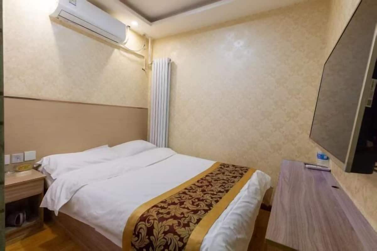 Ein Hotelzimmer mit Bett, Nachttisch, Lampe und einer Wandklimaanlage.