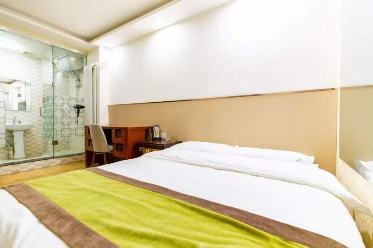 Ein Hotelzimmer mit Bett, Schreibtisch, Stuhl, Duschkabine und Waschbecken.