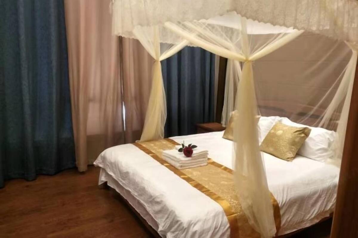 Una habitación con una cama bajo un dosel, una mesita de noche y cortinas.