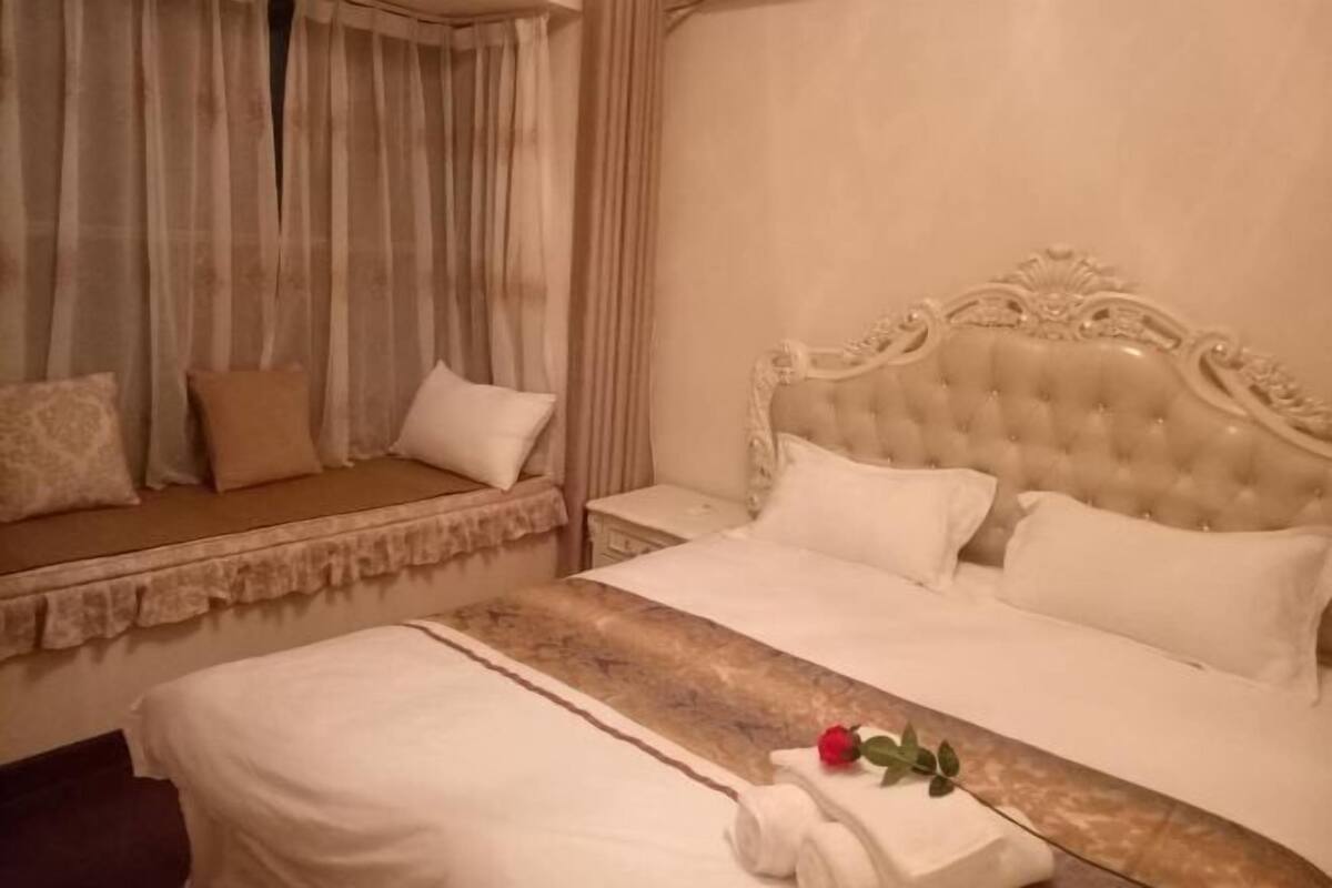 Una habitación de hotel con una cama grande, una mesita de noche, una ventana con cortinas y un sofá cama.