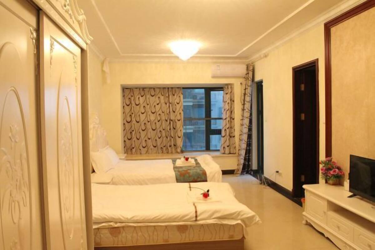 Habitación de hotel con dos camas, televisión y ventana con cortinas.