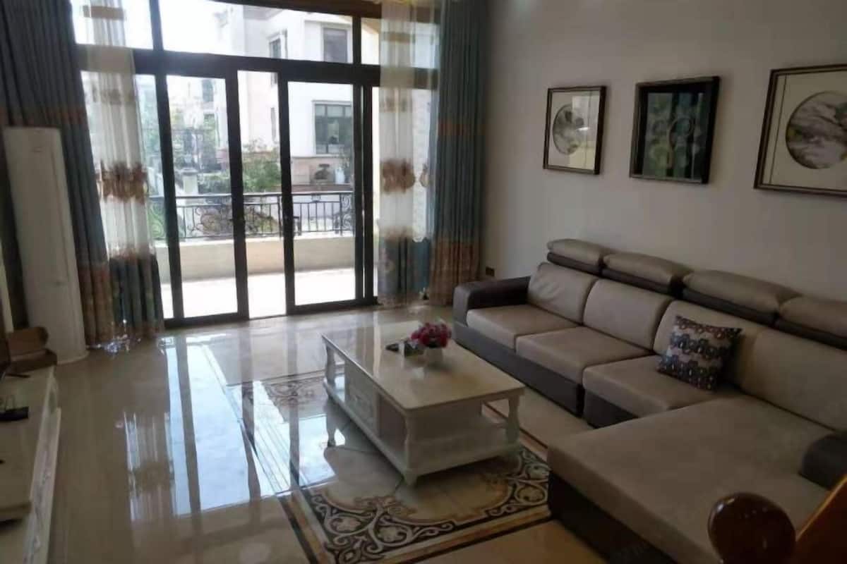 Amplia sala de estar con un sofá, una mesa de centro y vistas al balcón exterior a través de puertas de cristal.