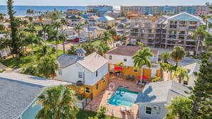 A residential area with a swimming pool, palm trees, and a view of the ocean. - Steps to BEACH/POOL/Downtown (Fort Myers Beach)