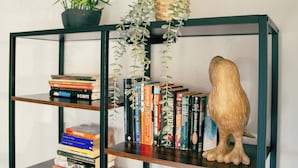 A bookshelf with books, a potted plant, and a wooden owl decoration.